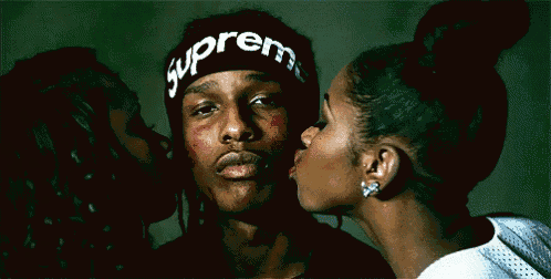 a man wearing a headband that says supreme is being kissed by two women
