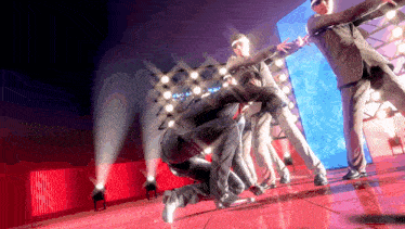 a man in a suit is kneeling on the floor in front of a group of men