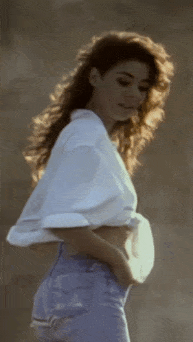 a woman in a white shirt and blue jeans is walking