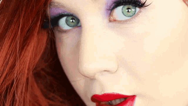 a close up of a woman 's face with green eyes and red lipstick