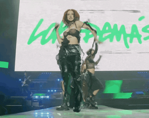 a woman is dancing in front of a large screen that says ' lana delmas '