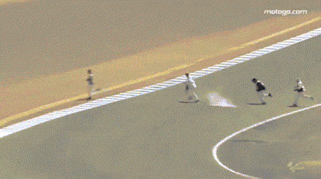 a pixelated image of two people running on a race track with the website motorgp.com visible in the corner
