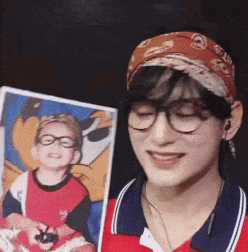 a young man wearing glasses and a headband is holding a picture of himself .