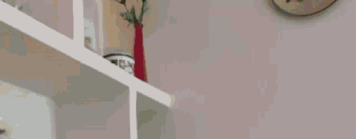 a shelf with a vase of flowers on it and a clock on the wall