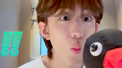 a close up of a person making a funny face with a stuffed animal in the background .