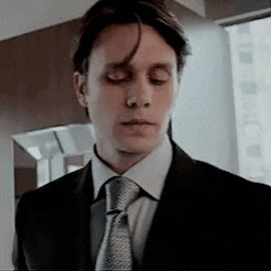 a man in a suit and tie is standing in front of a window with his eyes closed .