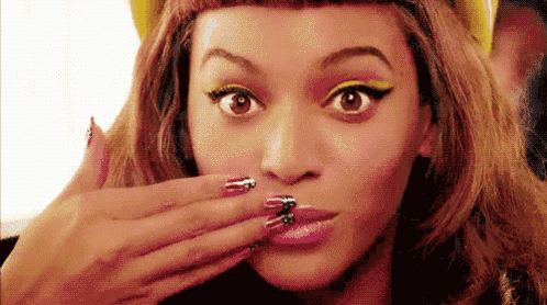 a close up of a woman covering her mouth with her hand while wearing a hat .