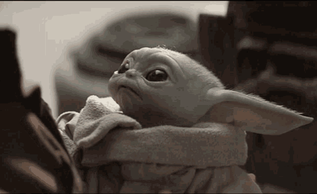 a baby yoda from star wars is sitting on a blanket .