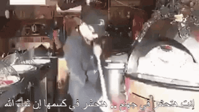 a man in a black hat is standing in a kitchen talking on a cell phone