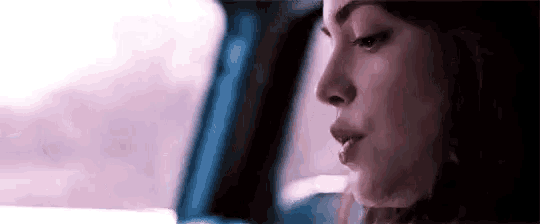 a close up of a woman 's face in a car looking out the window .