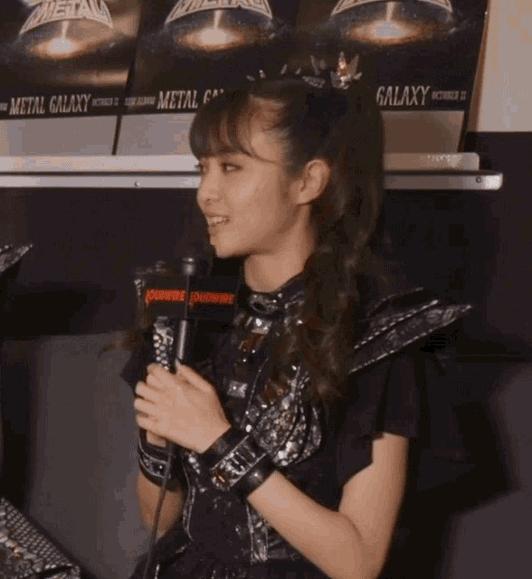 a girl holding a microphone in front of a metal galaxy sign
