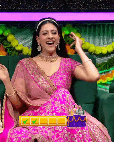 a woman in a pink dress is sitting on a green couch and laughing