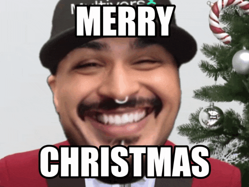 a man in front of a christmas tree with the words merry christmas written on his face