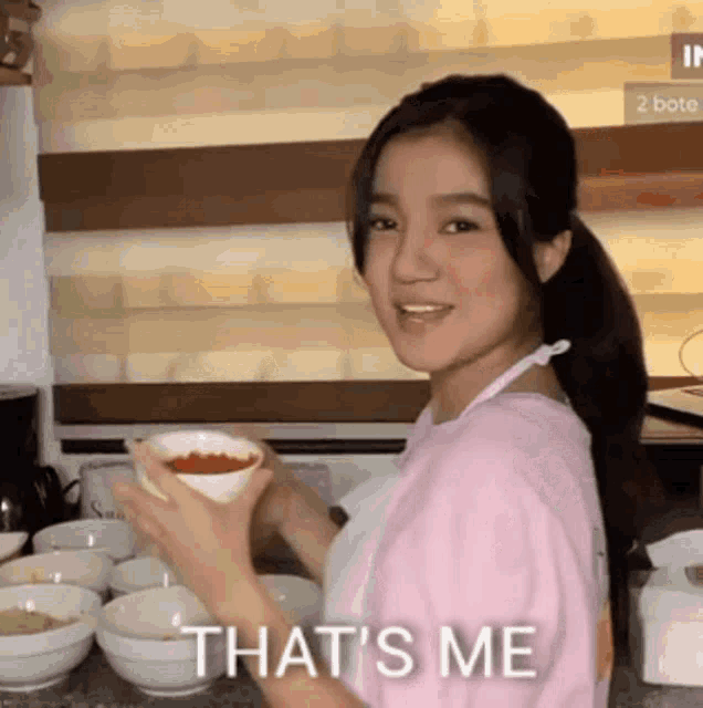 a woman is holding a bowl of food and says that 's me .