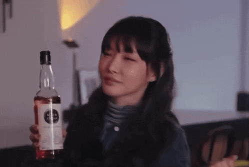 a woman is holding a bottle of alcohol with a label that says ' whisky ' on it