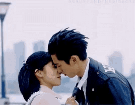 a man and a woman are kissing each other on the forehead .