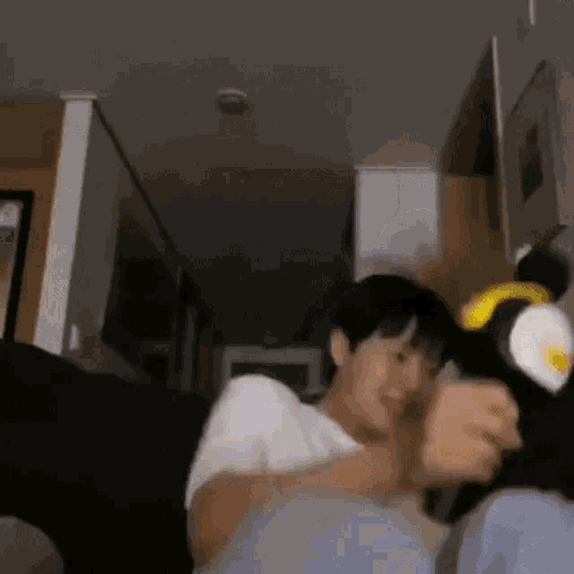 a man and a woman are sitting on a couch in a room . the man is wearing a penguin hat .