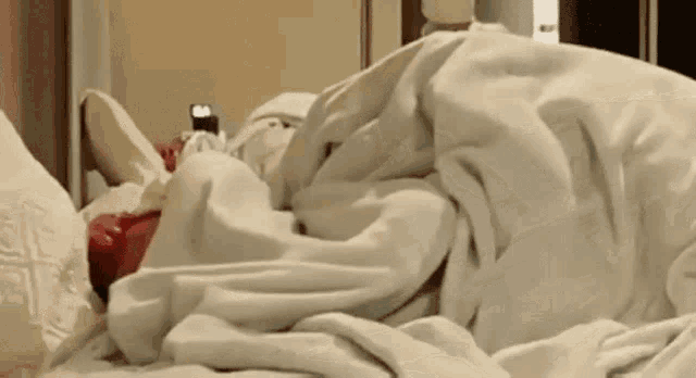 a person is laying on a bed with a red alarm clock