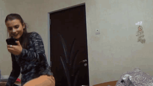a woman looking at her phone in front of a door