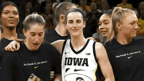 a woman wearing a iowa jersey is surrounded by other people