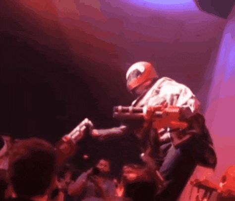 a man in a helmet is holding a gun in front of a crowd of people