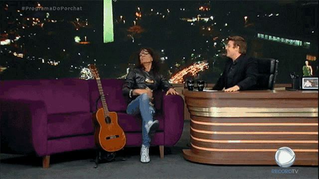 a woman sits on a purple couch with a guitar and a man sits at a desk with the word recordtv on it