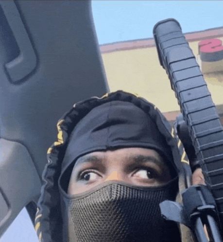 a person wearing a mask and holding a gun in a car