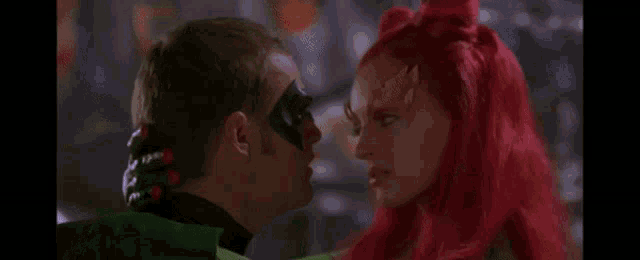 robin and poison ivy are standing next to each other and looking at each other in a movie .