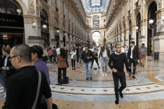 a group of people walking in front of a store that says prada