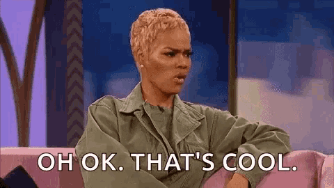 a woman is sitting on a couch and saying `` oh ok , that 's cool . ''