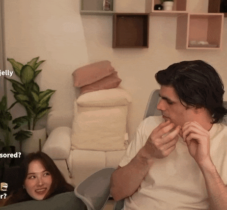 a man and a woman are sitting next to each other in a living room with a plant in the background ..