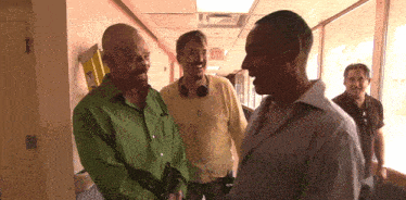 three men are standing in a hallway with an exit sign on the wall behind them