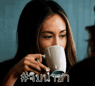a woman is drinking a cup of coffee with a foreign language written on it