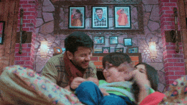 a man and woman are playing with a child in front of a wall with pictures on it