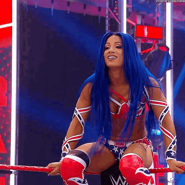 a woman with blue hair is sitting on a rope in a wrestling ring .