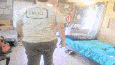 a person wearing an o'neill shirt is standing in a dorm room
