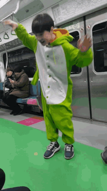 a boy in a green and white outfit is dancing on a subway train