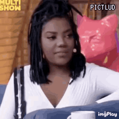 a woman with dreadlocks is sitting on a couch with a cup of coffee in front of her .