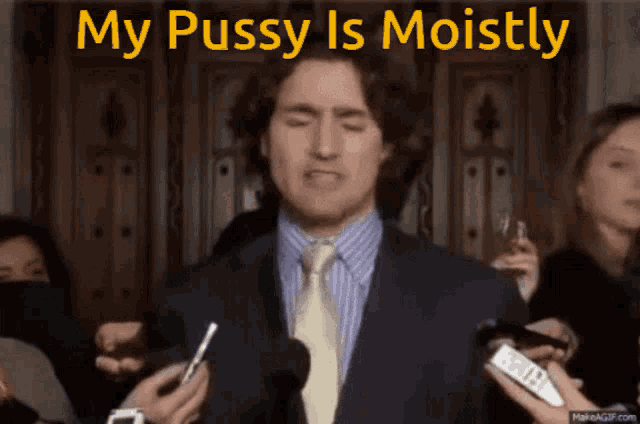 a man in a suit and tie is speaking into microphones with the words my pussy is moistly above him