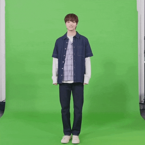 a young man is standing in front of a green screen ..