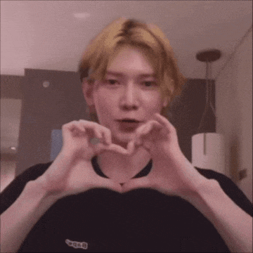 a young man is making a heart shape with his hands .