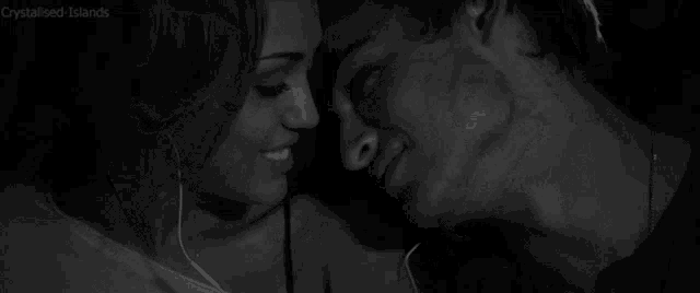 a black and white photo of a man and woman kissing while listening to music .