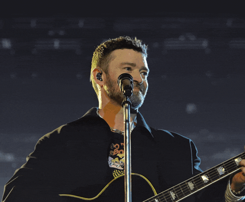 a man is singing into a microphone while playing a guitar