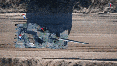 an aerial view of a military tank on a dirt road with a french flag flying in the background|833x469.95454545454544