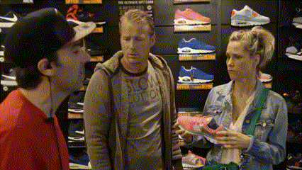 a man and a woman are standing in a shoe store looking at shoes .