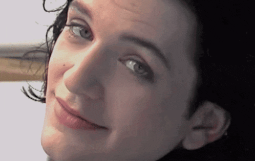 a close up of a woman 's face with blue eyes and black hair