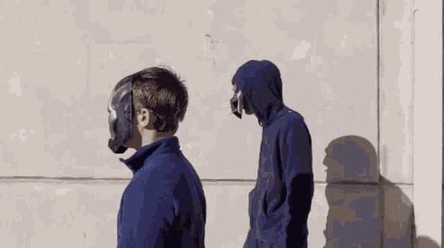 a man wearing a mask and a hoodie stands next to another man