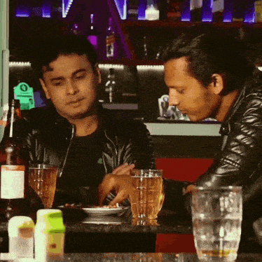 two men are sitting at a table with a bottle of johnnie walker
