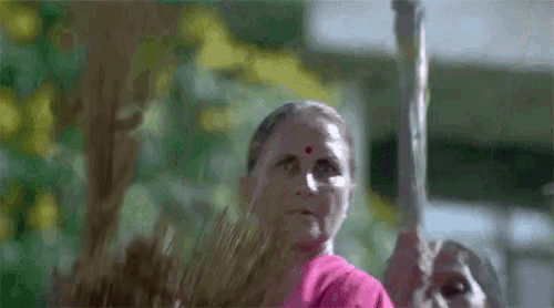 a woman with a red dot on her forehead is holding a broom