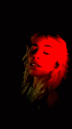 a woman 's face is lit up with a red light